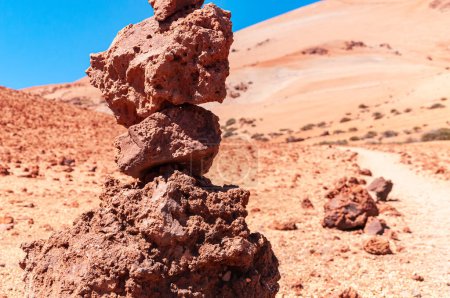 Pilar de una pila de piedras porosas rojas de roca volcánica sobre el telón de fondo del desierto, sendero, montañas y cielo azul. Parque Nacional del Teide, Tenerife