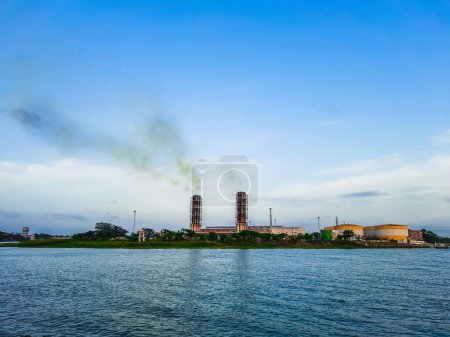 High pollution from power plant. Power plant on the coast. Ecology disaster concept. Power plant high pipes with black smoke moving up polluting atmosphere.
