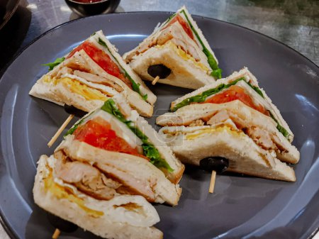 Sandwich con jamón, queso, tomates, lechuga, carne de pollo y pan tostado. Sándwich de club sobre la mesa.