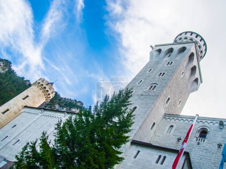 Téléchargez les photos : Neuschwanstein, célèbre château de contes de fées, princesses et amants, se distingue par le ciel bleu et les forêts sur fond de lacs - en image libre de droit