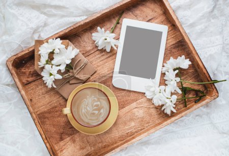 Foto de Composición de verano con taza de café, flores blancas en flor y e-reader con espacio para copiar. Plantilla para blog femenino redes sociales. - Imagen libre de derechos