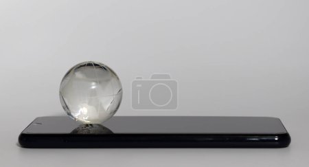 Téléchargez les photos : Un globe sur un smartphone. Concept de connexion numérique de terre. - en image libre de droit