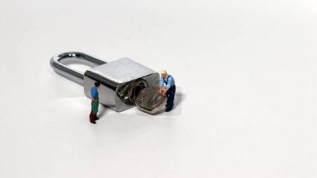Téléchargez les photos : Un personnage miniature essayant de choisir une serrure sur un fond blanc. Travailleurs miniatures et clés de sécurité utilisées comme systèmes de sécurité d'arrière-plan, piratage et concepts d'entreprise. - en image libre de droit