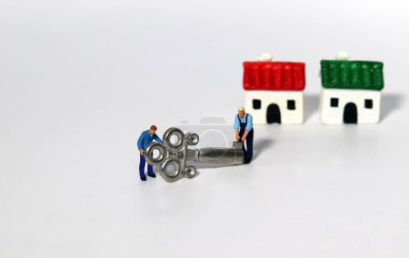 Miniaturmenschen, die Häuser und Metallschlüssel auf weißem Hintergrund bewegen. Das Konzept von Immobilien oder die Errungenschaft, das Eigentum und die Sicherheiten von Immobilien.