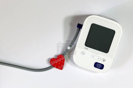 Rotes Herz und Blutdruckmessgerät zur Diagnose von Herzkrankheiten. Digitales Blutdruckmessgerät und Herz auf weißem Hintergrund.