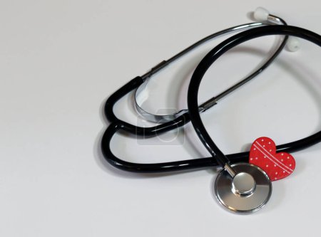 Stethoskop und rotes Herz auf weißem Hintergrund. Kardiologie und Gesundheitskonzept.