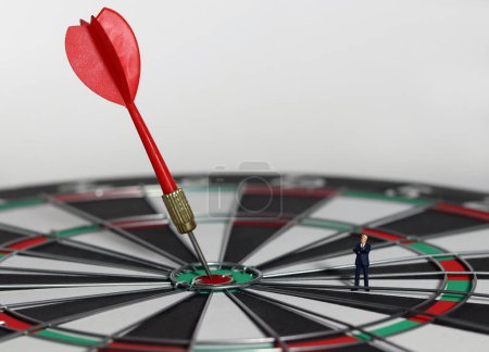 The red dart arrow in the middle of the dart paper is the goal of the business. An entrepreneur looking at arrows on a dartboard. Concept of business marketing plans and objectives. 