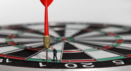 The red dart arrow is the goal of the business. The entrepreneur looking at the arrow from the dart board. The concept of business marketing plans and goals.