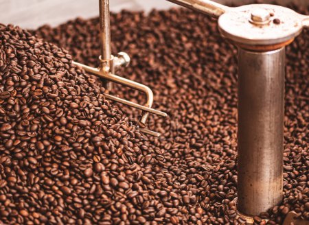 Photo for Roasting coffee beans in a professional old coffee roasting machine or roaster, close up - Royalty Free Image