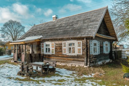 Téléchargez les photos : Belle ancienne maison traditionnelle en bois avec des pots en argile sur la clôture dans le village de Margionys, région de Dzkija ou Dainava, Lituanie, en hiver ou au printemps - en image libre de droit