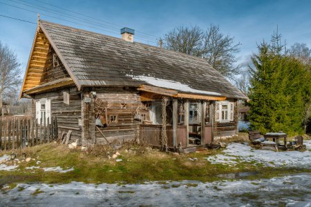 Téléchargez les photos : Belle ancienne maison traditionnelle en bois avec des pots en argile sur la clôture dans le village de Margionys, région de Dzkija ou Dainava, Lituanie, en hiver ou au printemps - en image libre de droit