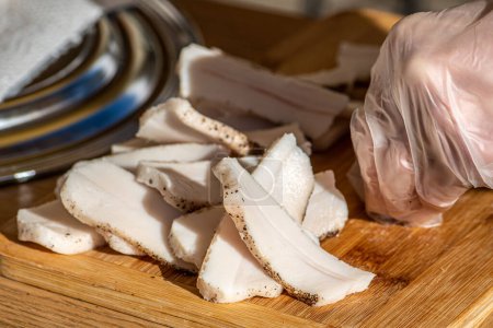 Photo for Pieces of lard or bacon, sliced thinly for consumption, on a wooden cutting board in a street food market, close up - Royalty Free Image