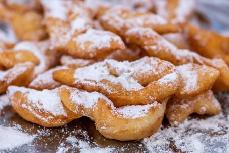Photo for Fried pastrie of Carnival, strips of fried dough typically made on Mardi Gras covered by powdered sugar, close up - Royalty Free Image