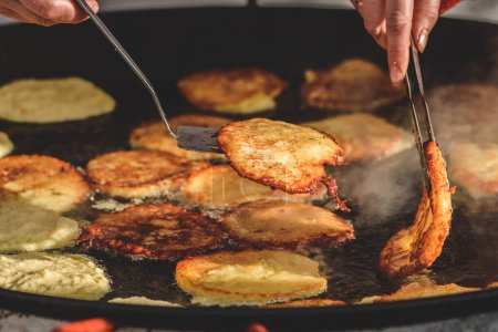 Photo for Frying traditional blini, blin or bulviniai blynai, potato pancakes on an open fire in a street food market - Royalty Free Image