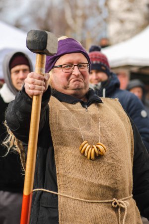Photo for Trakai, Vilnius, Lithuania - February 19 2022: Man with a hammer in a Lithuanian folk festival with traditional Ukrainian and Lithuanian, Eastern European small, crunchy, mildly sweet bread, vertical - Royalty Free Image