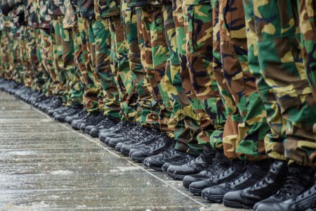 Botas militares y pantalones de camuflaje de muchos soldados en uniforme en fila durante un entrenamiento