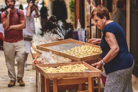 Photo for Bari, Italy - June 5 2023: Elderly local woman selling fresh orecchiette or orecchietta to tourists in Bari old town, handmade pasta made with durum wheat and water typical of Puglia or Apulia, Italy - Royalty Free Image