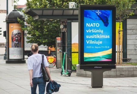 Photo for Vilnius, Lithuania - June 22 2023: Advertising banner informing about the upcoming Nato summit 2023 in the centre of Vilnius, capital of Lithuania with girl walking nearby - Royalty Free Image