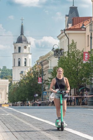 Téléchargez les photos : Vilnius, Lituanie - 20 août 2023 : Fille en vélo sur la route cyclable dans le centre-ville de Vilnius, Lituanie avec cloche et cathédrale en arrière-plan, verticale - en image libre de droit