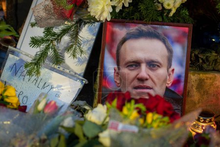 Foto de Vilna, Lituania - 20 de febrero de 2024: Flores y velas colocadas en el memorial espontáneo de Vilna para el líder de la oposición rusa Alexei Navalny, con retrato mojado de la nieve y las gotas de lluvia - Imagen libre de derechos