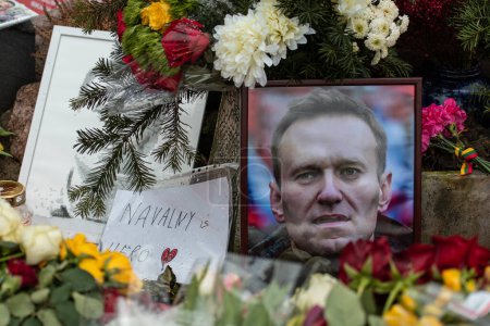 Téléchargez les photos : Vilnius, Lituanie - 21 février 2024 : Fleurs et bougies posées au mémorial spontané du chef de l'opposition russe Alexei Navalny, avec portrait et messages mouillés par la neige et les gouttes de pluie - en image libre de droit
