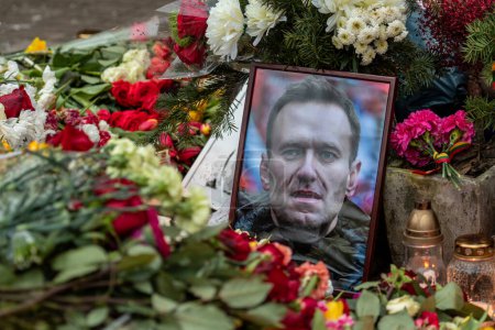 Foto de Vilna, Lituania - 21 de febrero de 2024: Flores y velas colocadas en memoria espontánea del líder de la oposición rusa Alexei Navalny, con retratos y mensajes mojados de la nieve y las gotas de lluvia - Imagen libre de derechos