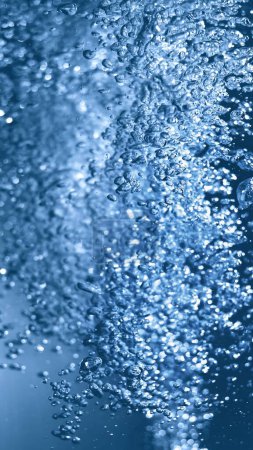 Foto de Pelusa efervescente e higiene limpia, rejuvenecer cosméticos o energías renovables. Ilustración 3D de burbujas transparentes de gas azul bajo el agua en macro de marco completo de cerca con enfoque selectivo. - Imagen libre de derechos
