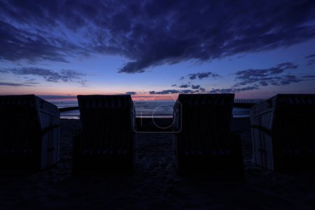 Téléchargez les photos : SUNSET OVER THE COAST - Soirée romantique sur la plage de la mer avec des paniers de plage en arrière-plan - en image libre de droit