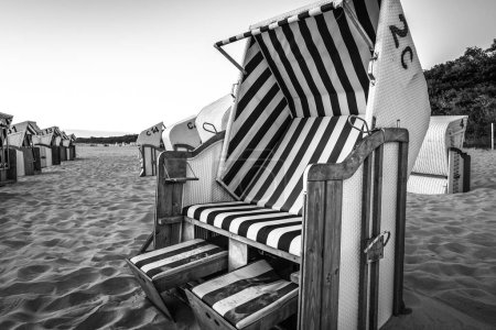Téléchargez les photos : PLAGE DE LA MER - Des paniers de plage au lever du soleil attendent les baigneurs - en image libre de droit