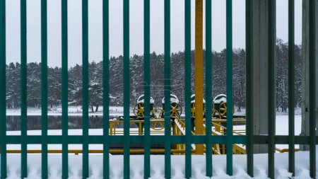 Foto de CONSTRUCCIÓN HIDROTÉCNICA - Rueda de engranaje y otros elementos de un vertedero en un lago en el paisaje de nieve e invierno - Imagen libre de derechos