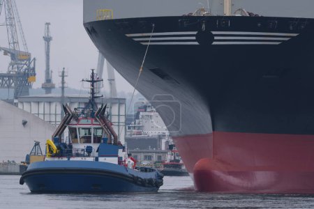 MARITIME TRANSPORT - A tugboat maneuvers with a ship in a seaport