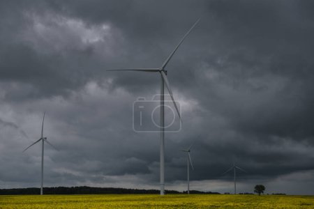Foto de AGRICULTURA Y PREVISIÓN DE VIENTO - Dramáticas nubes de lluvia negra sobre molinos de viento - Imagen libre de derechos