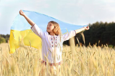hermosa chica ucraniana lleva ondeando bandera azul y amarillo de Ucrania contra el cielo y el fondo del campo. Bandera de Ucrania es un símbolo de independencia. Celebrar la Constitución Día de la bandera de la independencia