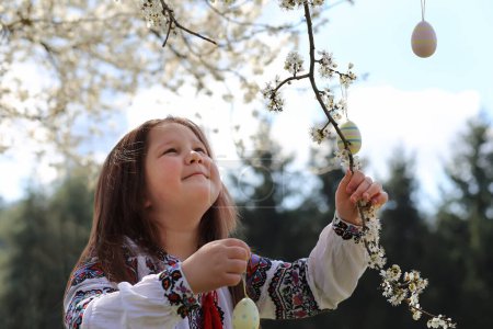 Téléchargez les photos : Jolie fille ukrainienne portant vyshyvanka décorer l'arbre avec des œufs de Pâques. heureuse famille célébrant Pâques. - en image libre de droit