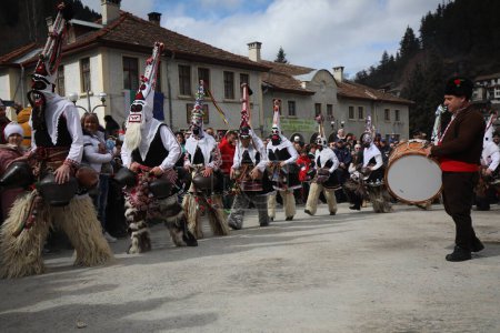 Téléchargez les photos : Shiroka laka, Bulgarie - 5 mars 2023 : Des gens avec un masque appelé danse Kukeri et se produisent pour effrayer les esprits maléfiques au Festival des Jeux de la Mascarade "Pesponedelnik" à Shiroka laka, Bulgarie. - en image libre de droit