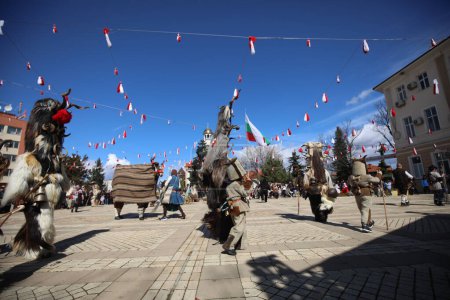 Téléchargez les photos : Elin Pelin, Bulgarie - 11 mars 2023 : Festival de mascarade à Elin Pelin, Bulgarie. Les gens avec un masque appelé danse Kukeri et effectuer pour effrayer les esprits maléfiques. - en image libre de droit