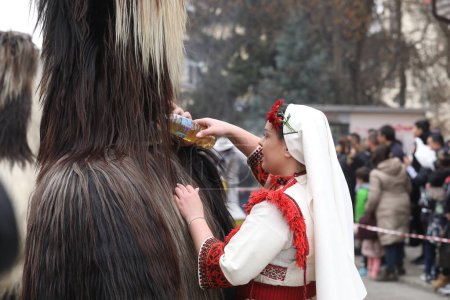 Téléchargez les photos : Kyustendil, Bulgarie - 10 février 2024 : Premier festival de mascarade "Djamala" à Kyustendil, Bulgarie. Les gens avec un masque appelé danse Kukeri et effectuer pour effrayer les esprits maléfiques. - en image libre de droit