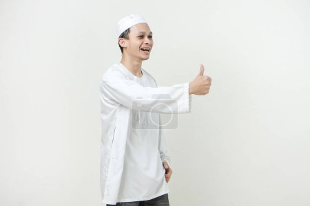 Foto de Musulmán asiático dar el pulgar hacia arriba gesto en el fondo aislado. Gente religiosa concepto de estilo de vida islámico - Imagen libre de derechos