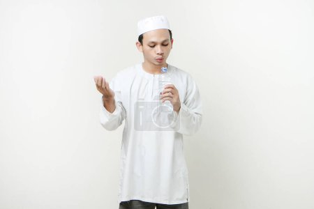 Foto de Asiático musulmán hombre celebración botella de agua y orar. sosteniendo la palma hacia arriba. Gente religiosa Islam concepto de estilo de vida. celebración Ramadán y ied Mubarak. sobre fondos aislados - Imagen libre de derechos