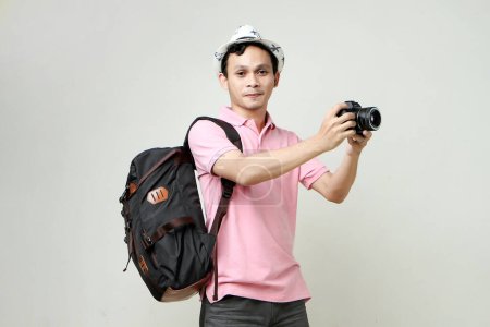 Foto de Hombre asiático mochilero tomando fotos con cámara digital. concepto de viaje. sobre fondo aislado - Imagen libre de derechos