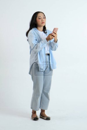pleine longueur shoot de asiatique indonésien femme tenant smartphone avec faim geste sur fond isolé