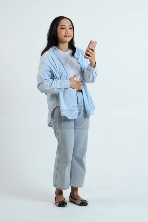 pleine longueur shoot de asiatique indonésien femme tenant smartphone avec faim geste sur fond isolé