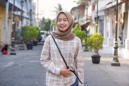 glückliche asiatische muslimische Frau, die durch Kota Lama oder die Altstadt von Semarang, Zentraljava, Indonesien, streift. Reisekonzept