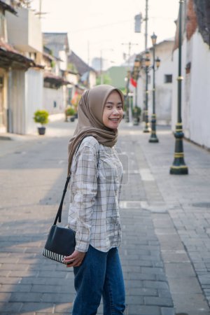 glückliche asiatische muslimische Frau, die durch Kota Lama oder die Altstadt von Semarang, Zentraljava, Indonesien, streift. Reisekonzept