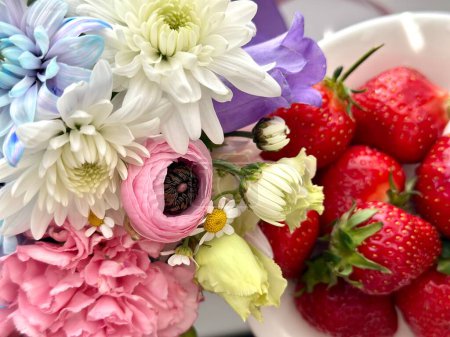 Téléchargez les photos : Superbe bouquette de fleurs sur fond de fraises, carte postale estivale, slow life - en image libre de droit