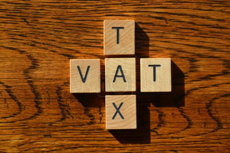 Foto de Impuesto y IVA, acrónimo del Impuesto sobre el Valor Añadido en letras de alfabeto de madera aisladas sobre fondo de madera texturizada - Imagen libre de derechos