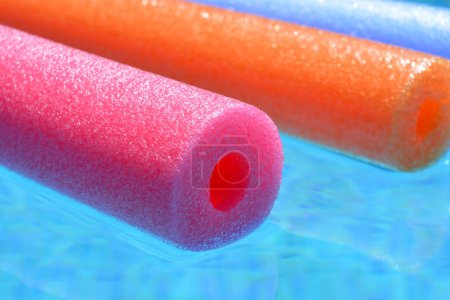 Photo for Summer vibes, colourful  pink, orange and blue polyethylene swim noodles floating in swimming pool - Royalty Free Image