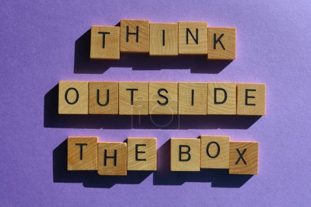 Foto de Think Outside The Box, palabras en letras de alfabeto de madera aisladas sobre fondo púrpura - Imagen libre de derechos