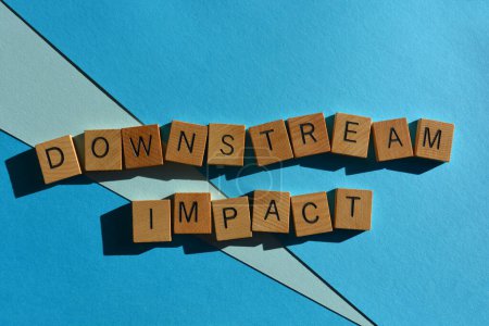 Téléchargez les photos : Downstream Impact, phrase à la mode dans les lettres de l'alphabet en bois isolé sur fond bleu - en image libre de droit