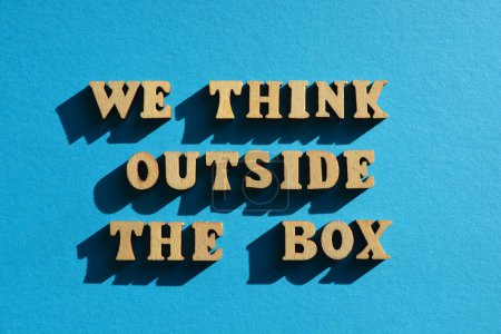 Téléchargez les photos : We Think Outside The Box, words in wooden alphabet letters isolated on blue background - en image libre de droit